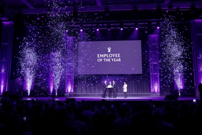 Jahresabschlussfeier mit Awards – Employee of the Year Mitarbeitende erhalten Auszeichnungen auf einer festlichen Jahresabschlussfeier mit Bühne, Applaus und Lichteffekten